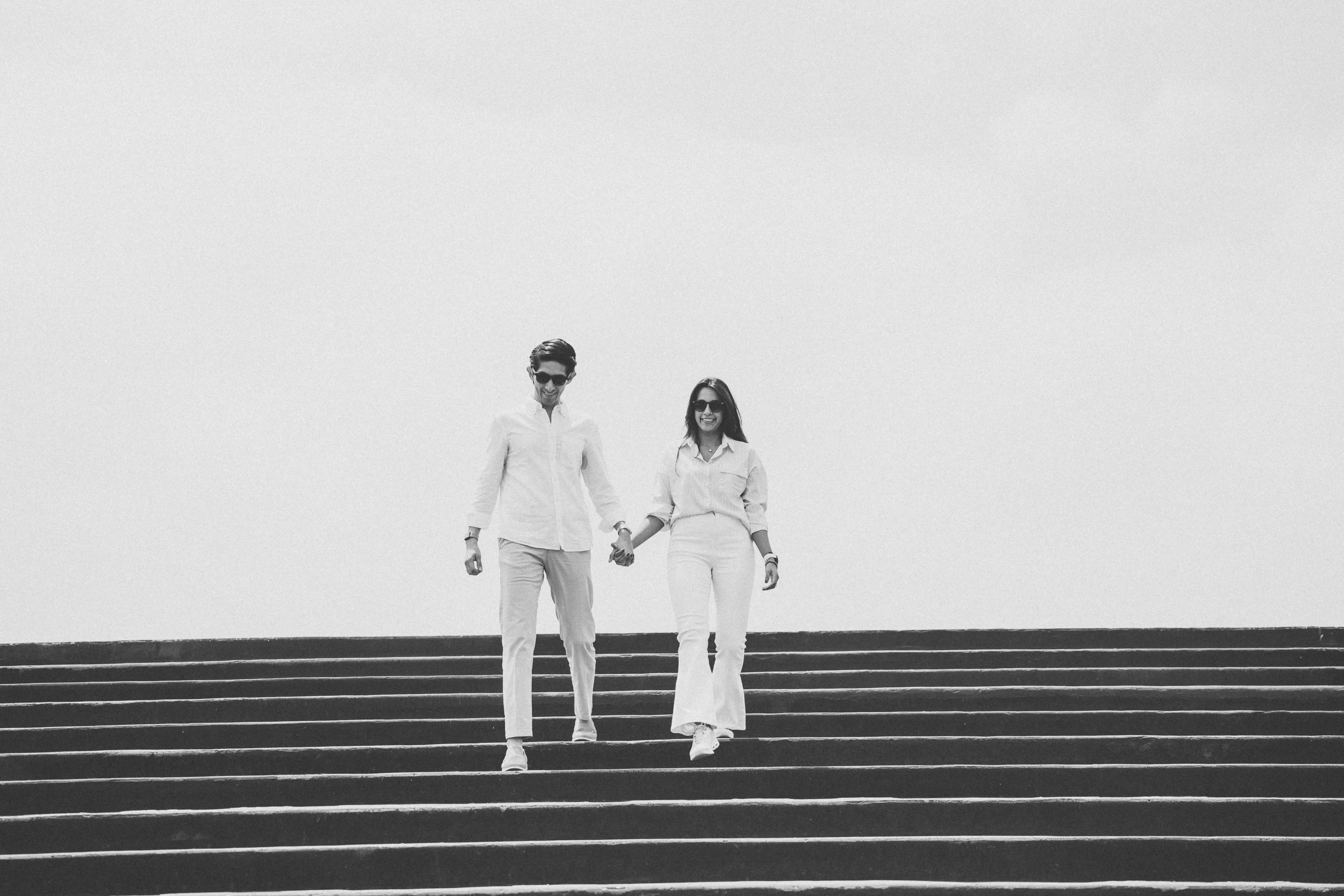 Andrea y Augusto bajan juntos una escalinata, en blanco y negro